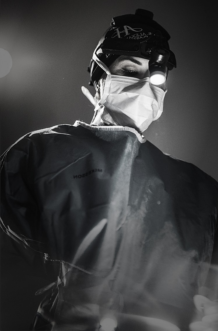 Surgeon wearing protective gear and headlamp.