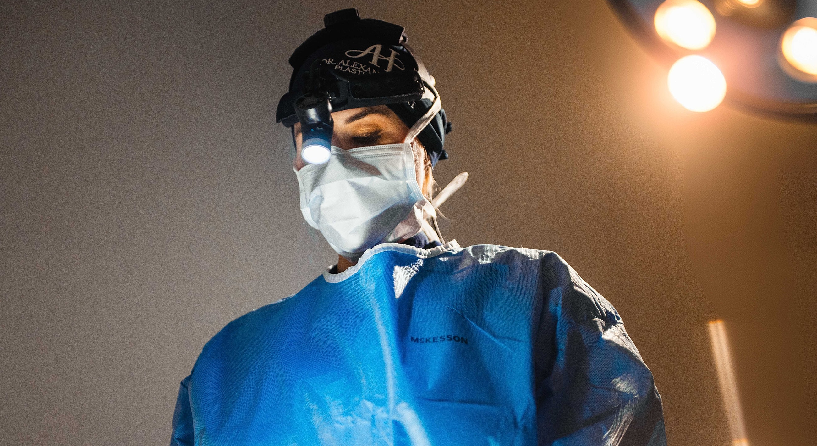 Surgeon wearing mask and headlamp in operating room